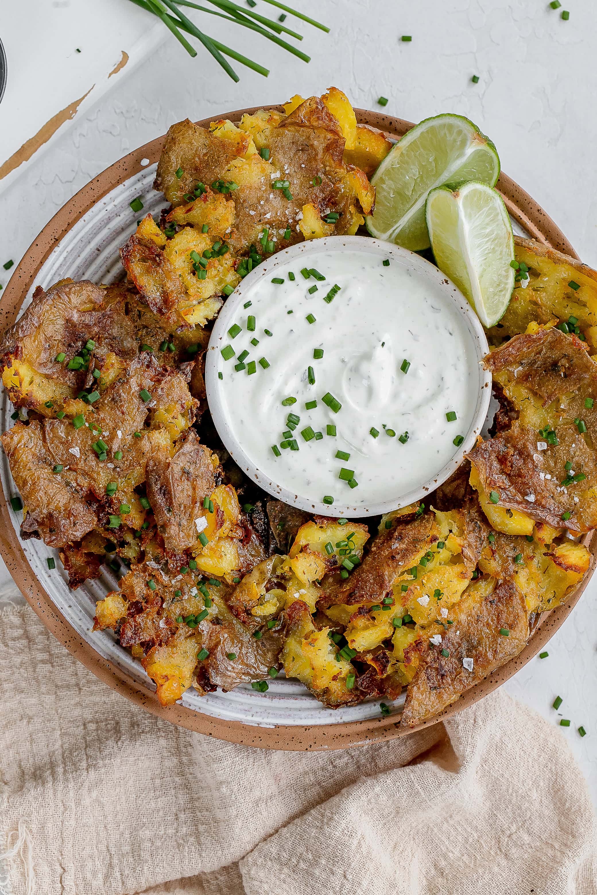 ranch smashed potatoes on a plate with dipping sauce. 