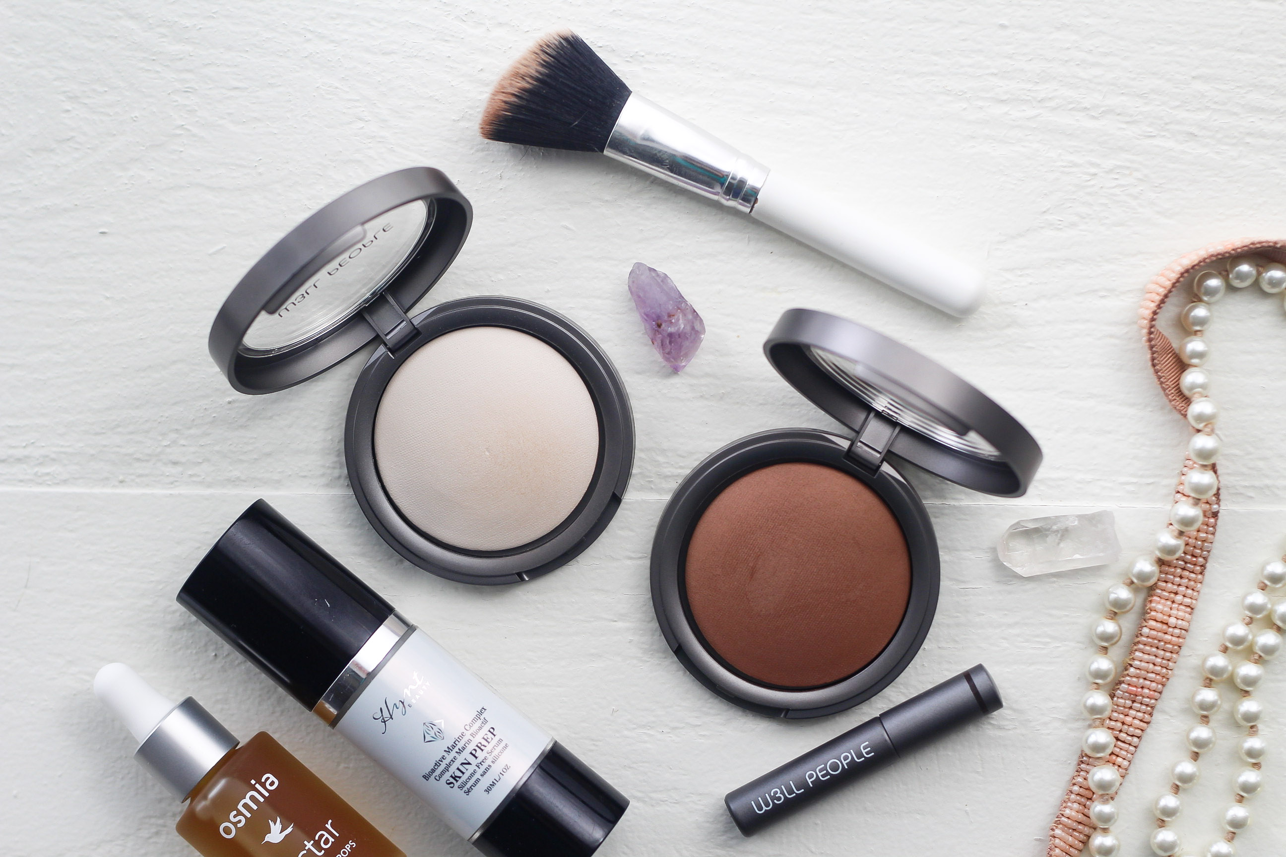 makeup products laid out on white board.