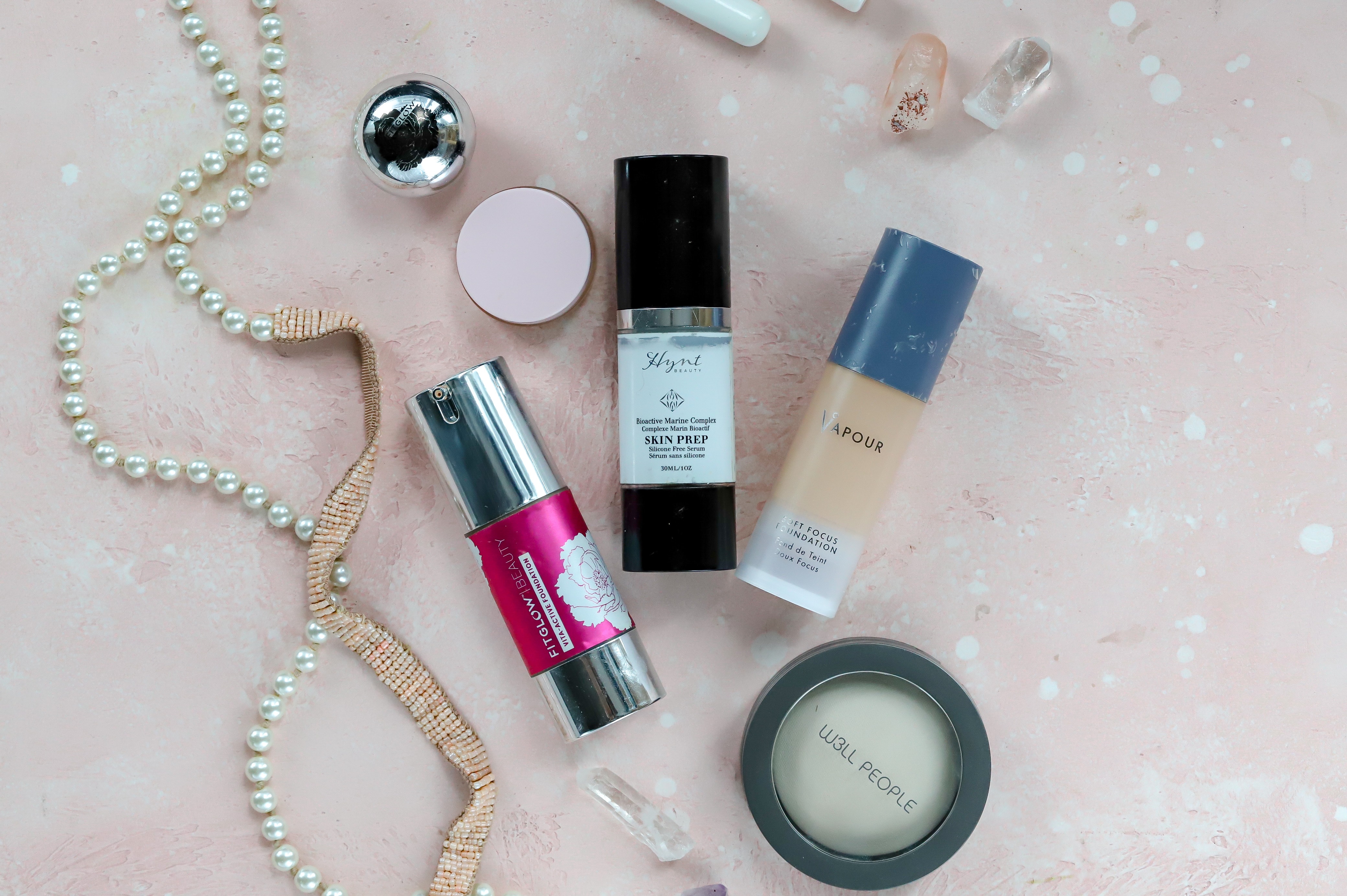 foundation bottles laid out on pink table.