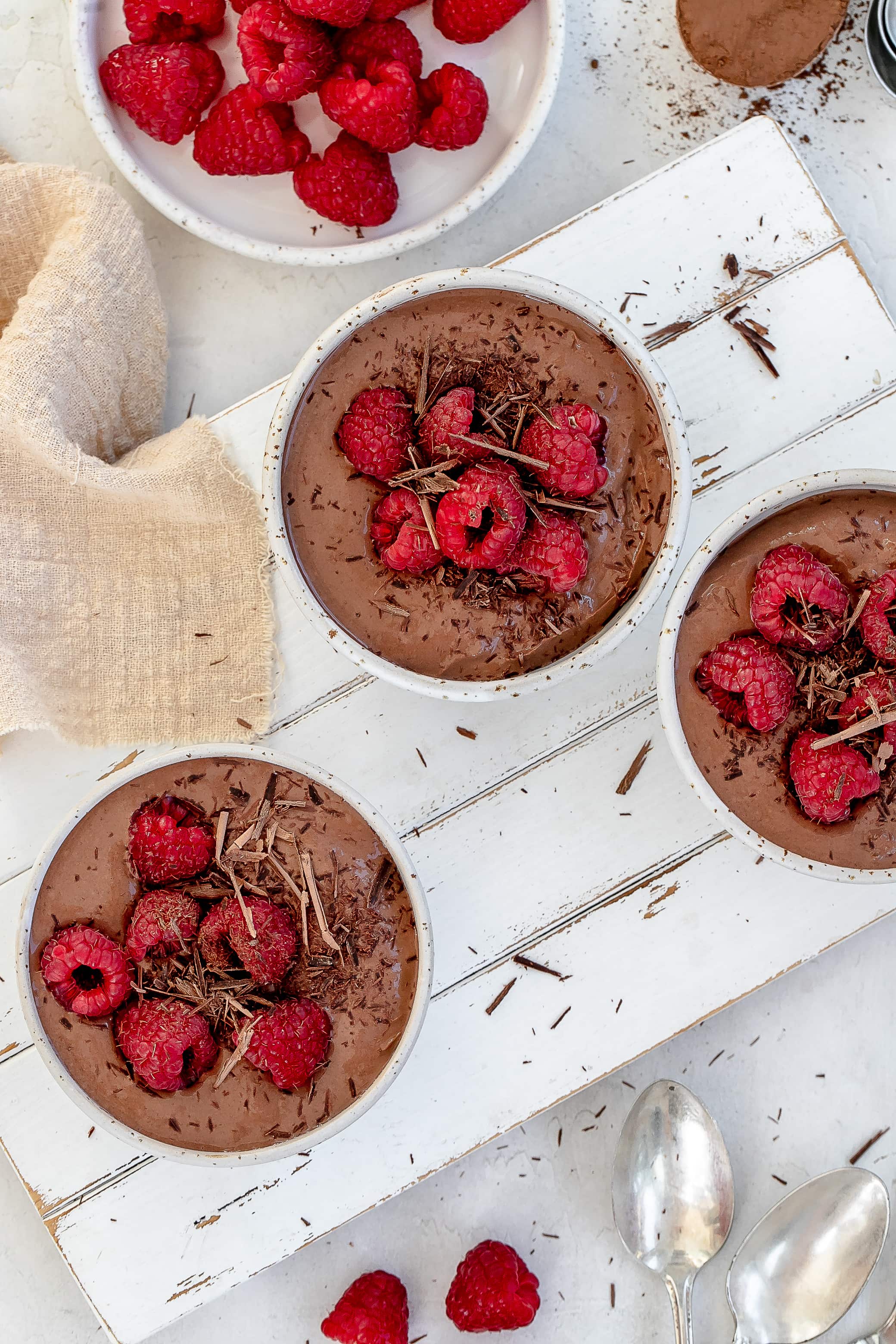 high protein Greek yogurt chocolate mousse in bowls with raspberries on top.