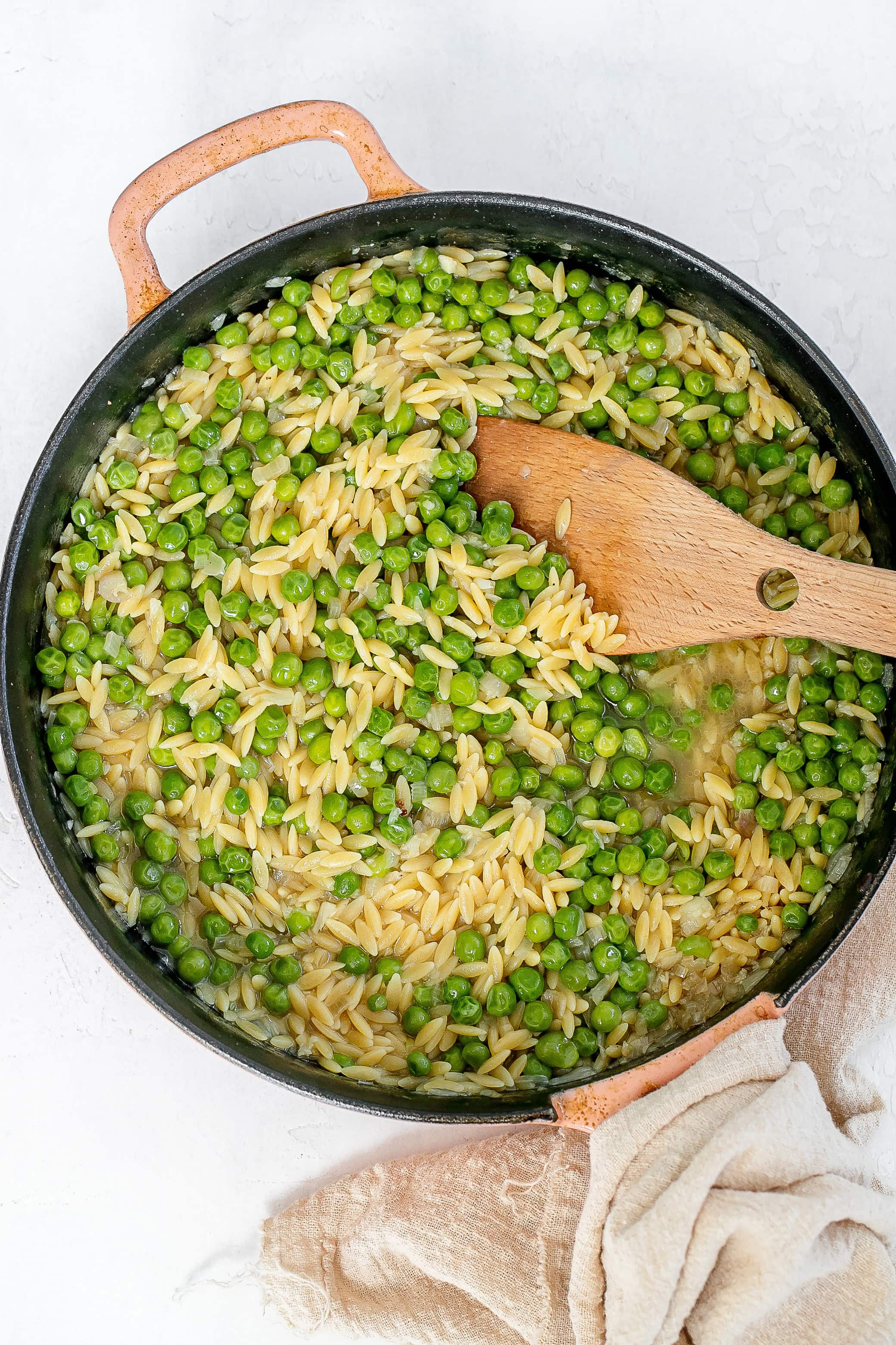 orzo and peas cooked in skillet.