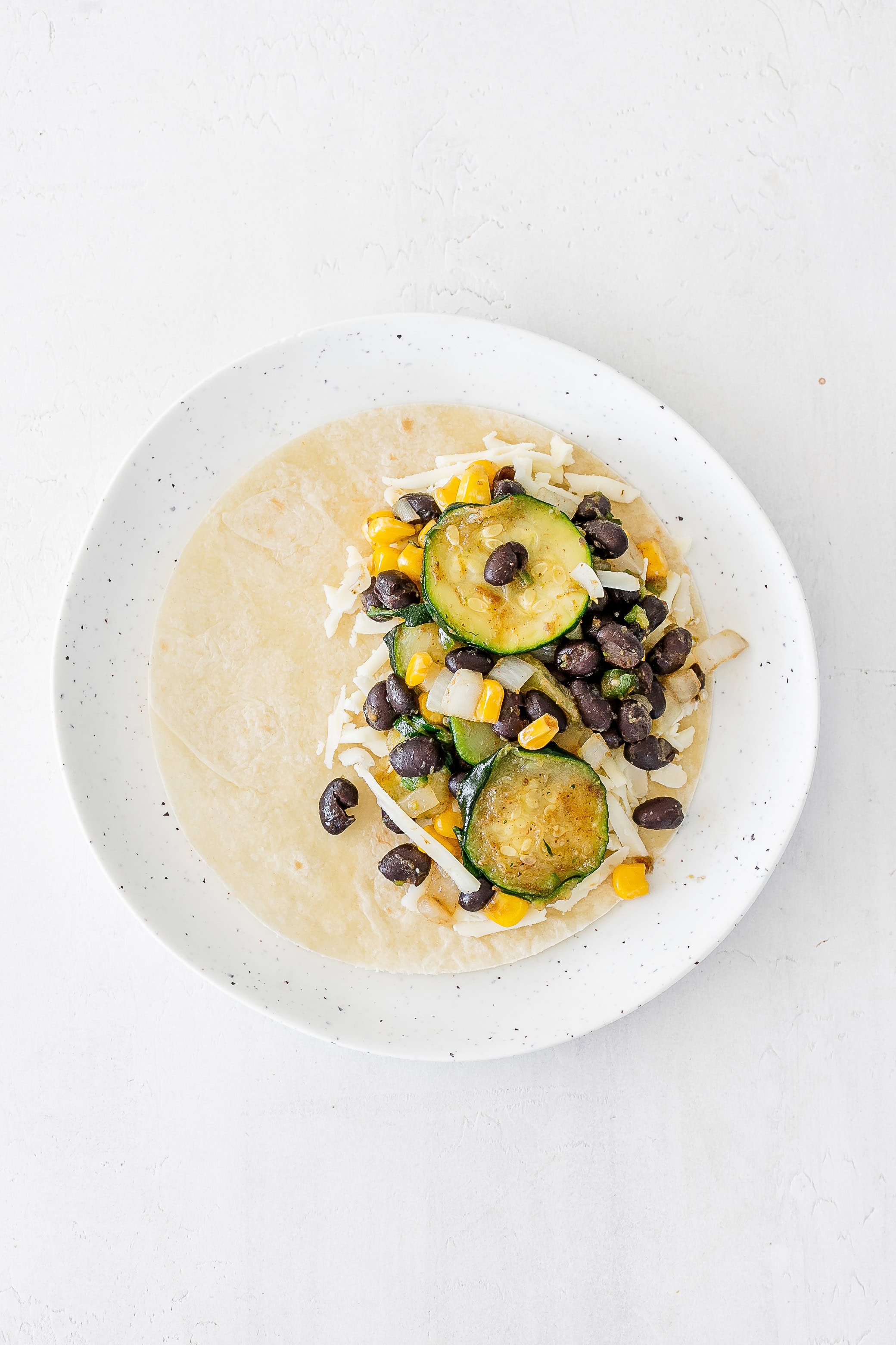 tortilla laid flat with toppings added. 