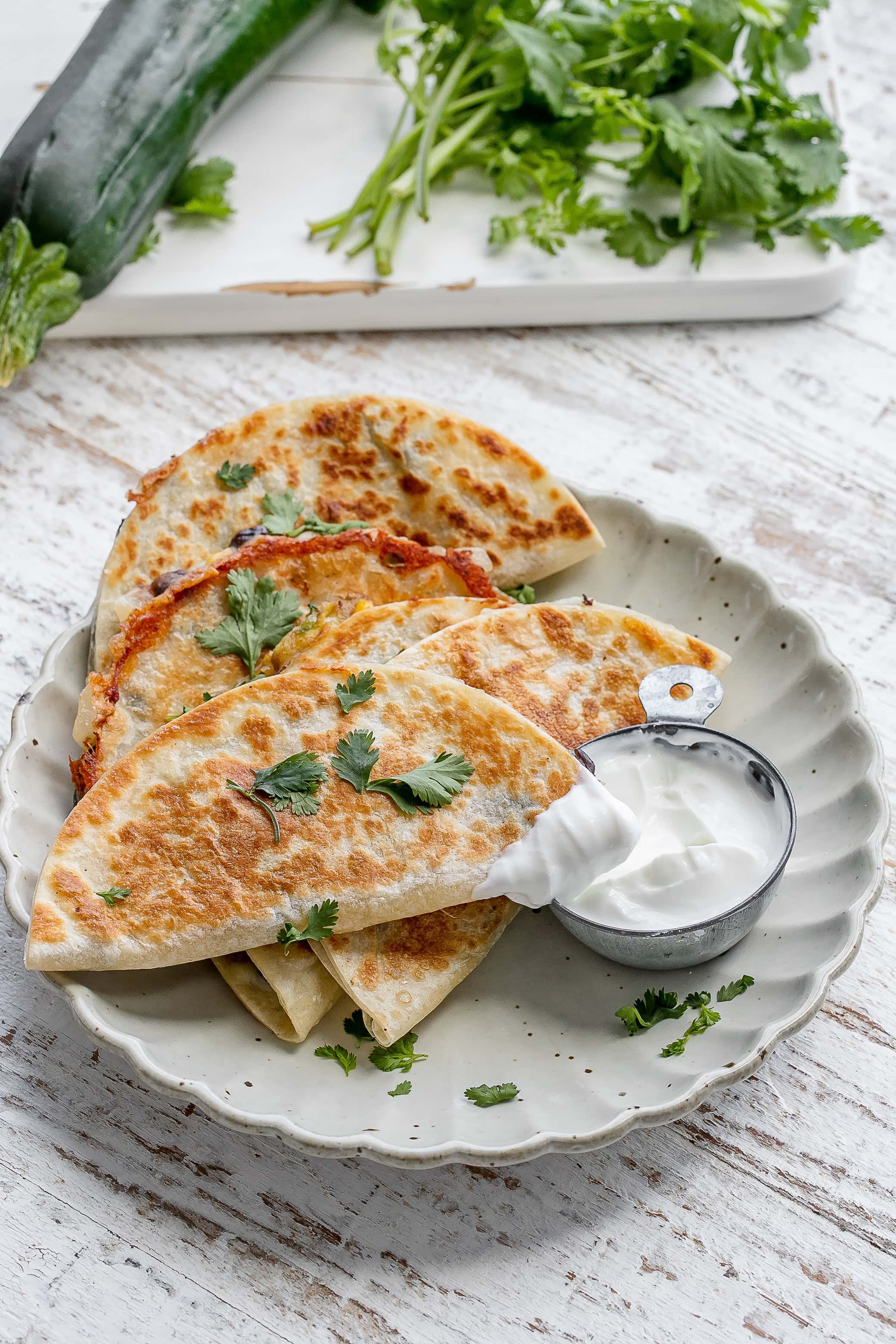 zucchini quesadillas on a plate with yogurt dip.