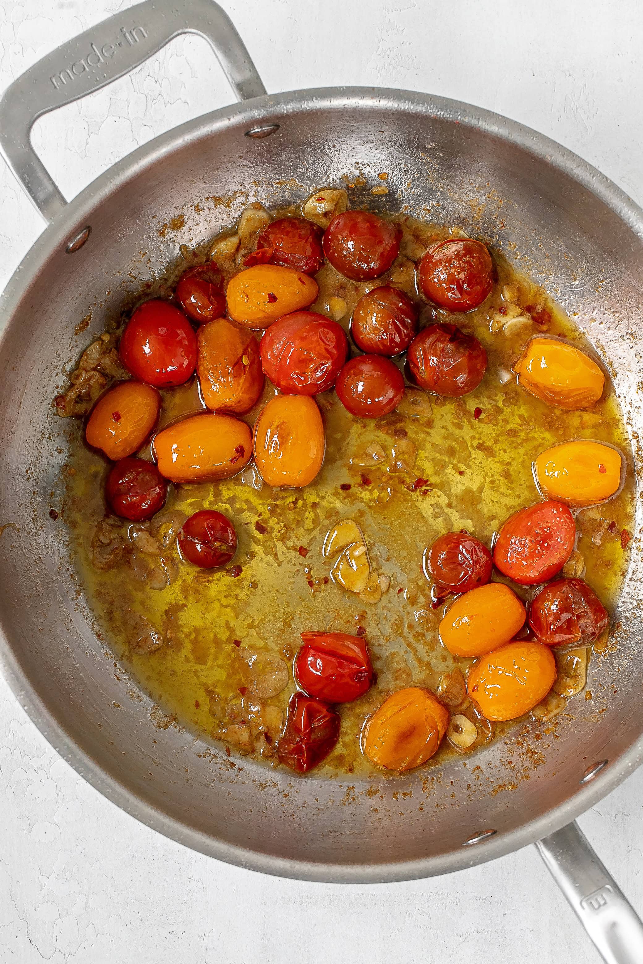garlic added to tomatoes in skillet.