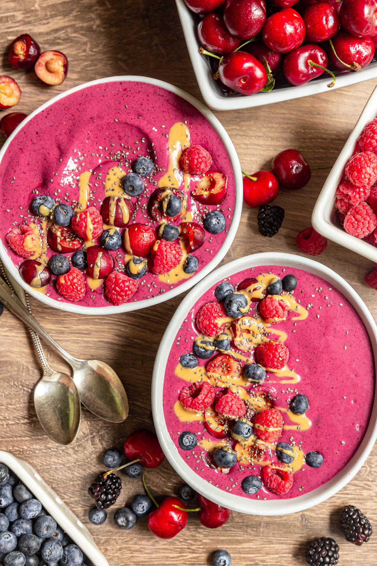Two Cherry Berry Smoothie Bowls with boxes of berries and cherries.