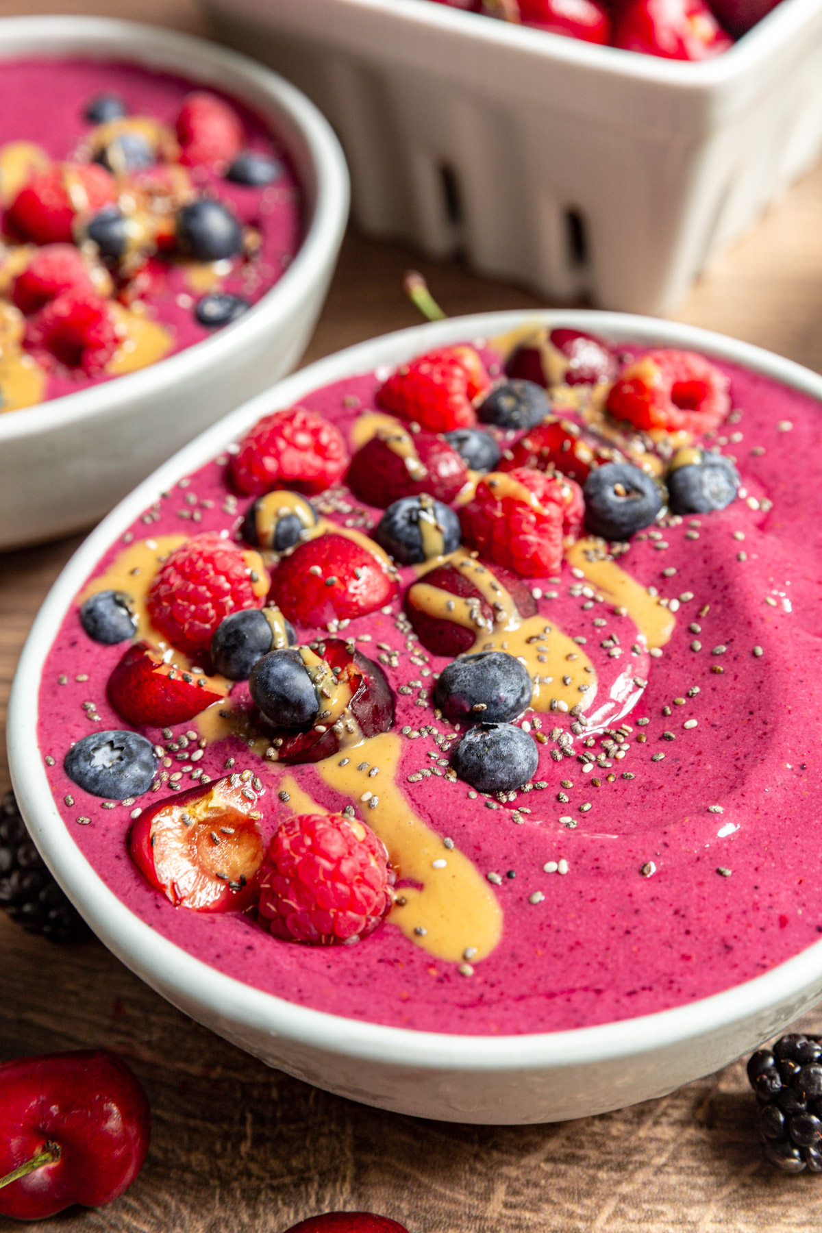 A side view of the toppings on a Cherry Berry Smoothie Bowl, including berries, a peanut drizzle, and chia seeds.