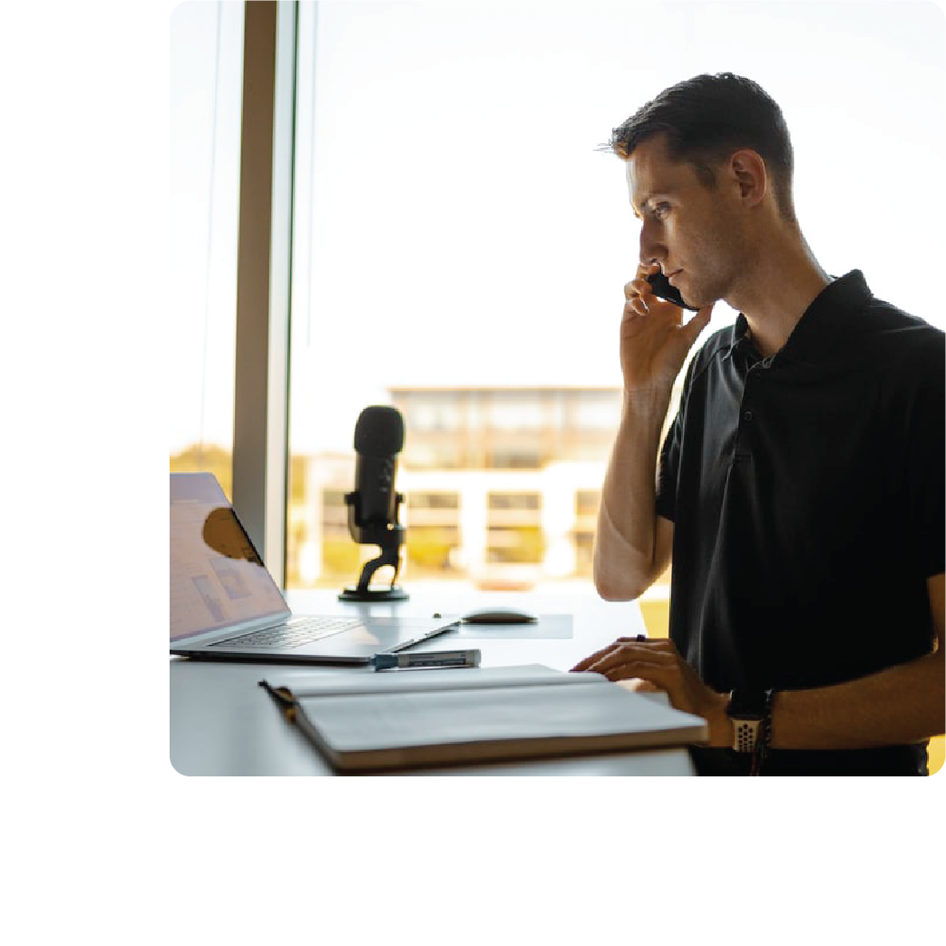 an individual working from a desk and making a phone call