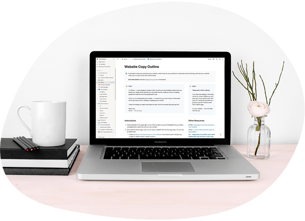 Laptop on a table with books, pencils, a coffee mug, and a vase with flowers.