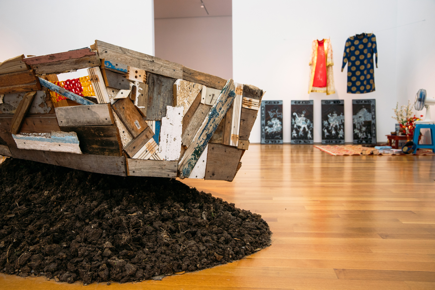 Image of an installation by Brandon Tho Harris containing a boat sculpture in the foreground and other sculptural objects in the background.