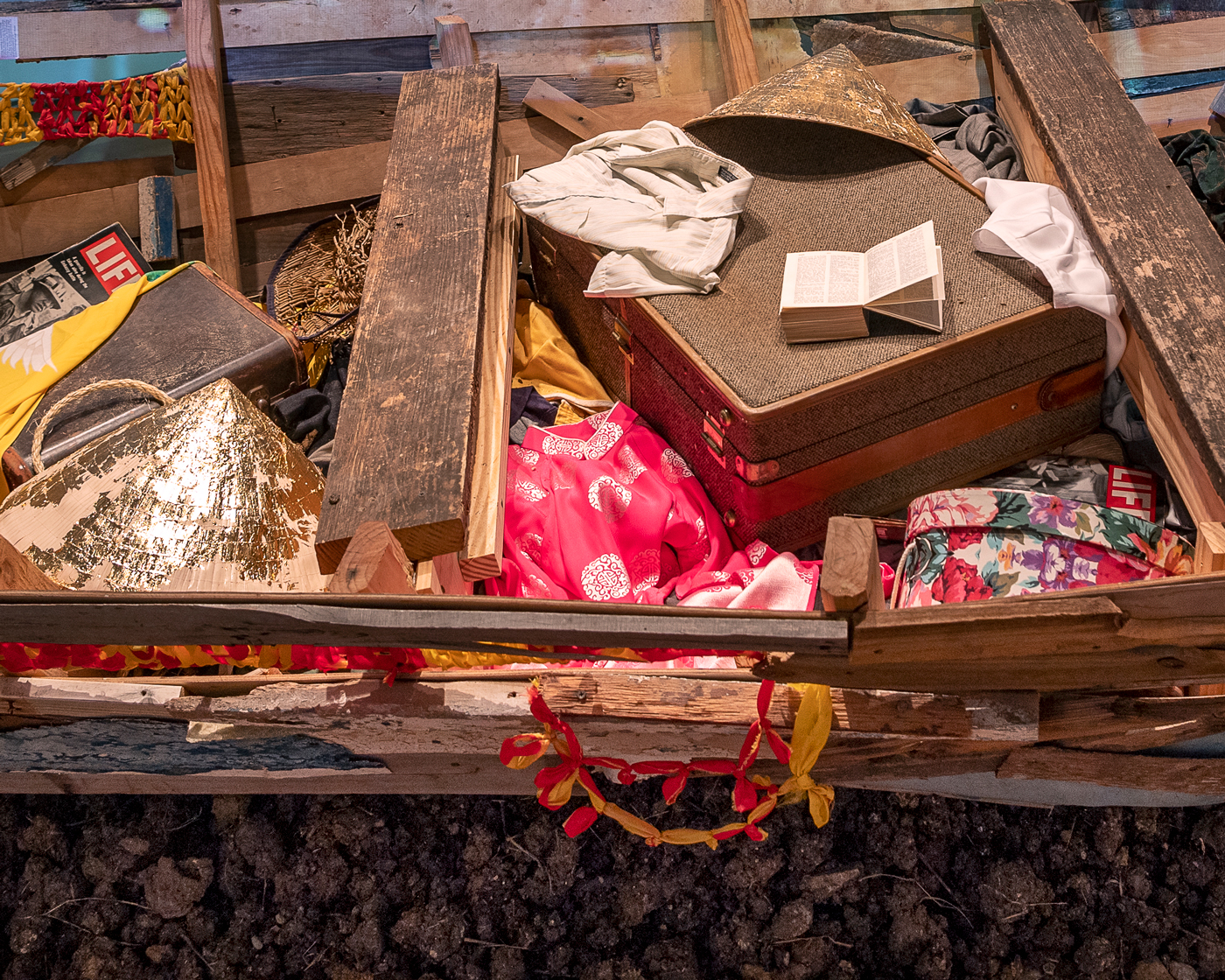 Image of an installation by Brandon Tho Harris containing a boat sculpture in the foreground and other sculptural objects in the background.