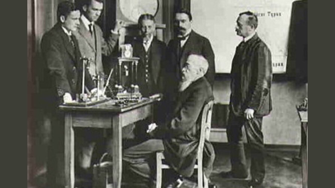 Wilhelm Wundt seated at his desk with 5 peers surrounding him.