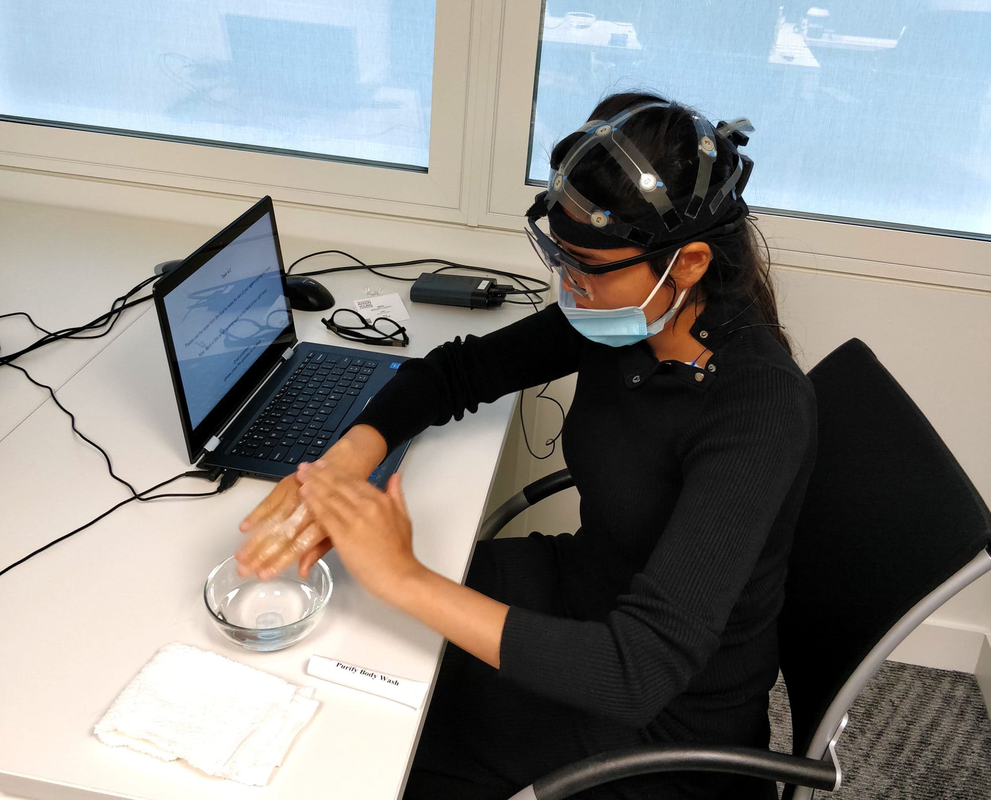 A woman with EEG equipment working on a computer.