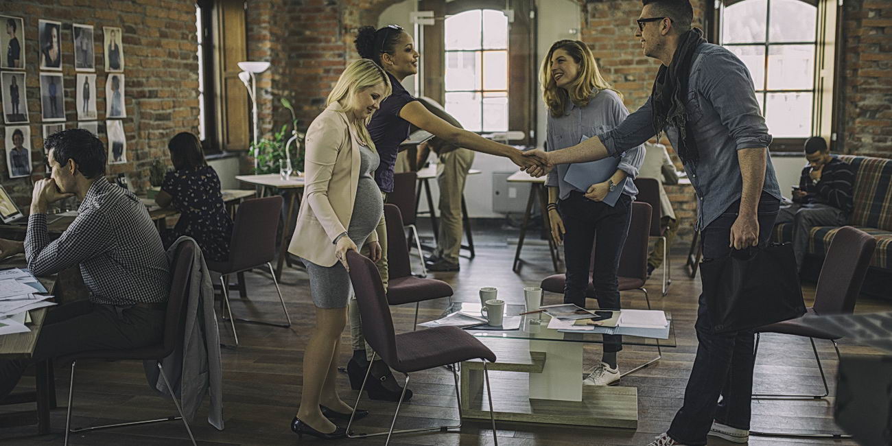 Two people shaking hands in a large modern coworking office