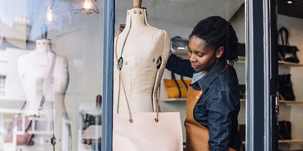 a handmade handbag store owner dresses her shop window