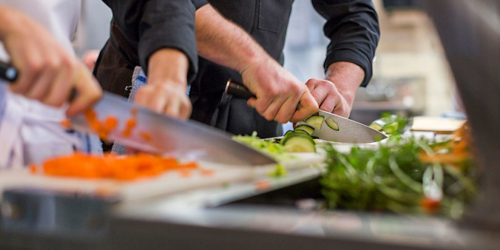 2 sous chefs slicing vegetables