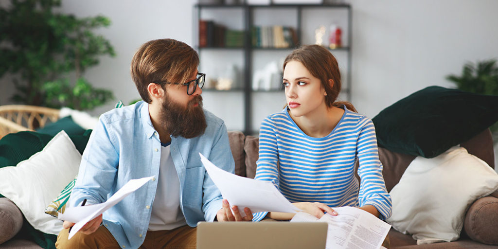 married couple with bills receipts documents and laptop at home