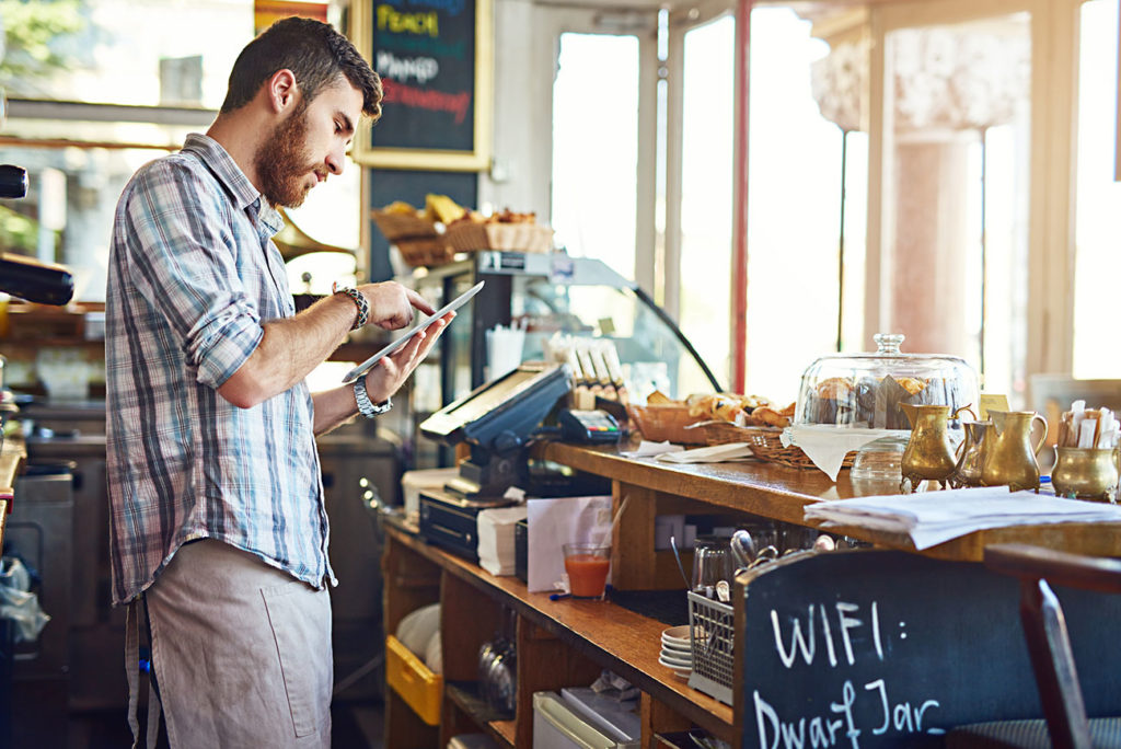 smiling man calculating profit margin in tea and coffee shop
