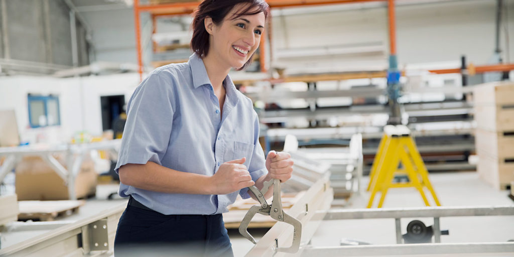 Female worker using vise grip tool in manufacturing plant