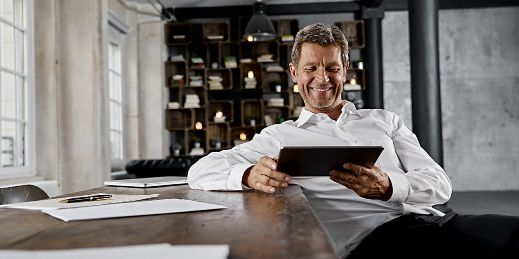 Smiling mature man using digital tablet in loft office