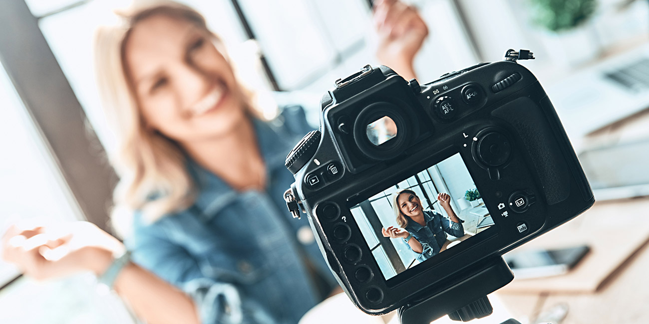 Beautiful young woman in casual wear smiling while recording video
