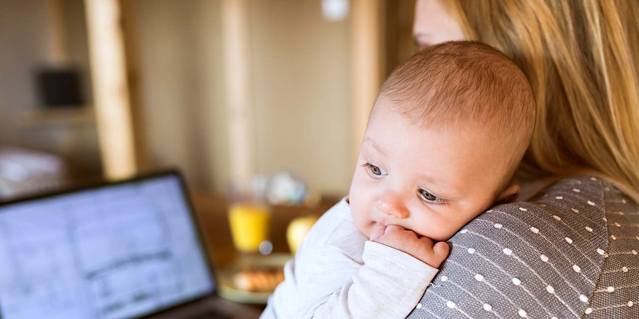 mother at home with baby on maternity leave using laptop