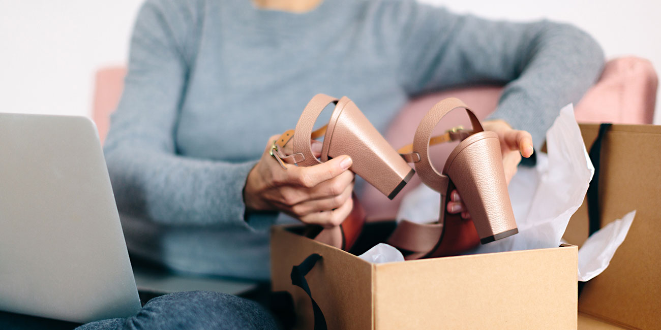 Cropped view of woman using laptop, unpacking shoes from box