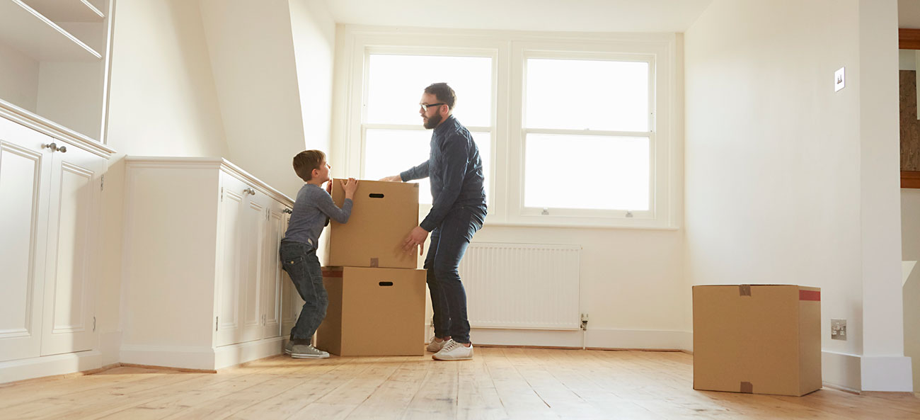 a self-employed father and his son stacking cardboard boxes in new home