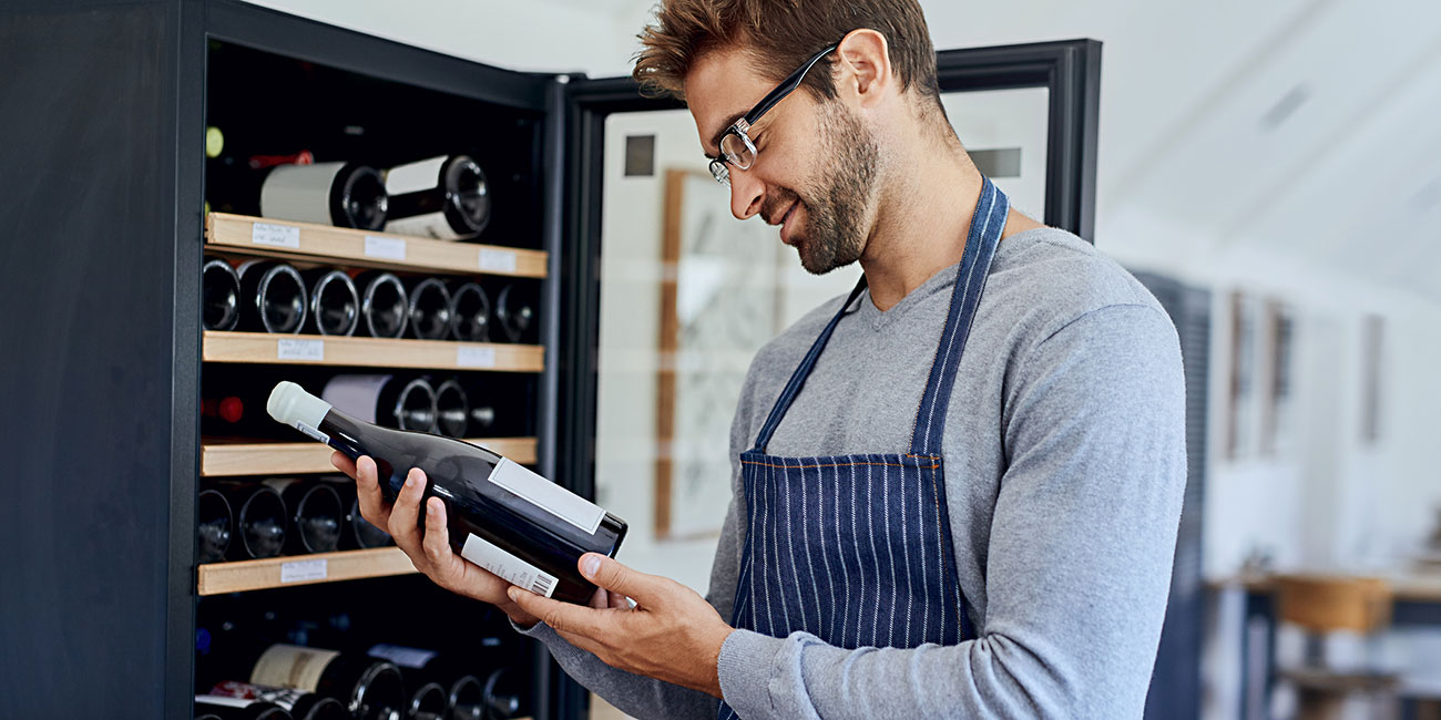 Shot of a handsome young man choosing a bottle of wine in a restaurant