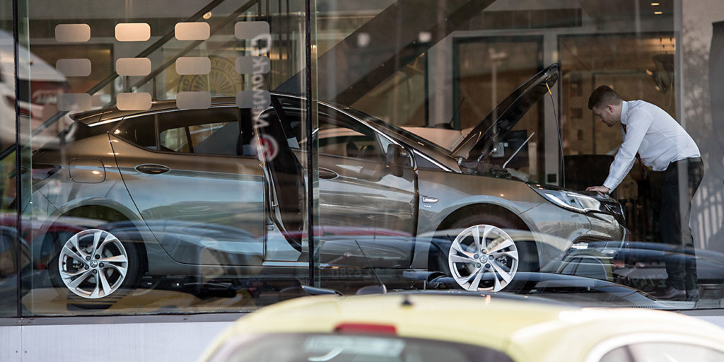 An employee checks under the bonnet of a Vauxhall car at a Vauxhall dealership