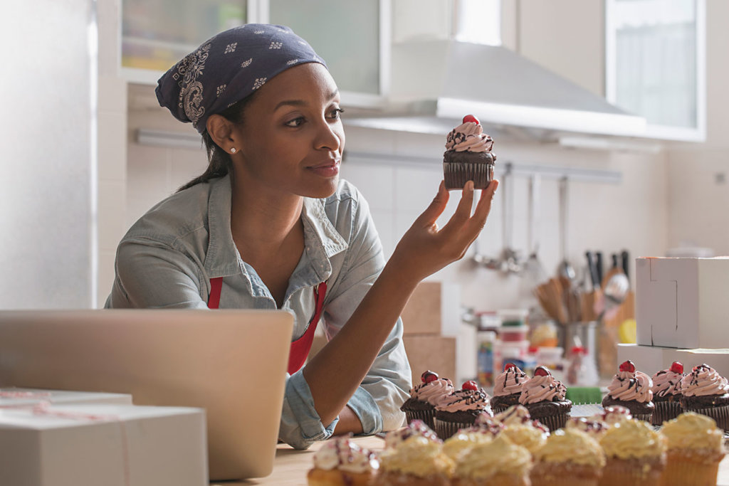 female baker admiring cupcake in commercial kitchen