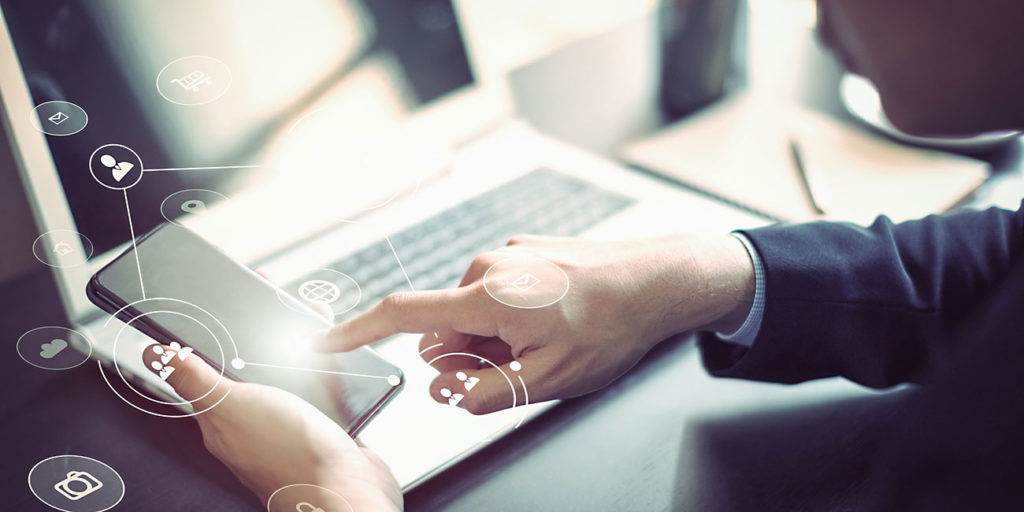Businessman hand working with mobile phone and laptop computer with technology digital graphic