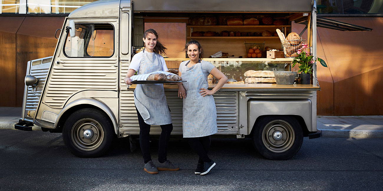 confident saleswomen standing outside foot truck parked on city street