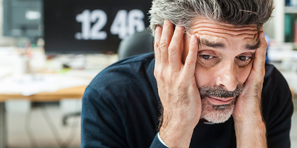 Mature man sitting in office with head in hands
