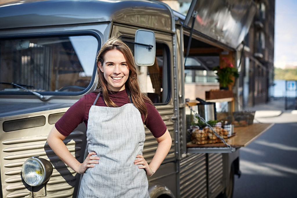 smiling young woman entrepreneur standing in front of a food truck