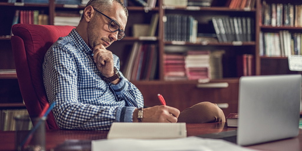 male adult writing notes in home office