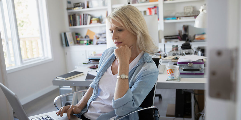 blonde woman using laptop in home workspace