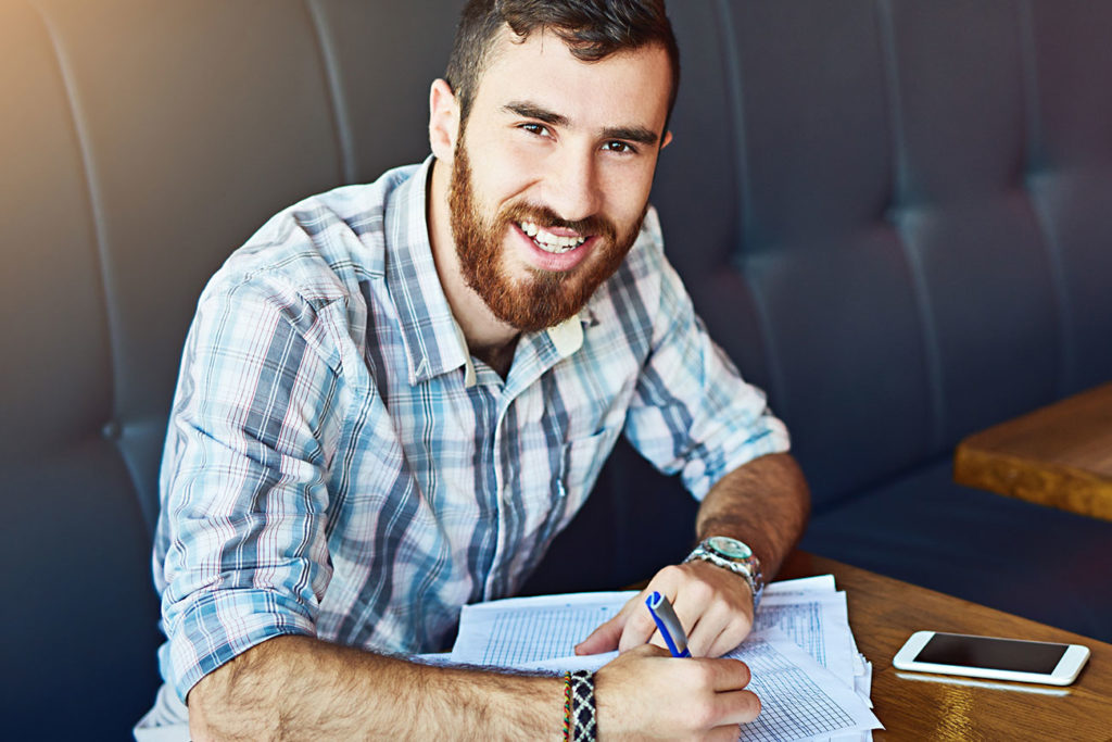 seated male shop owner calculating profit margin