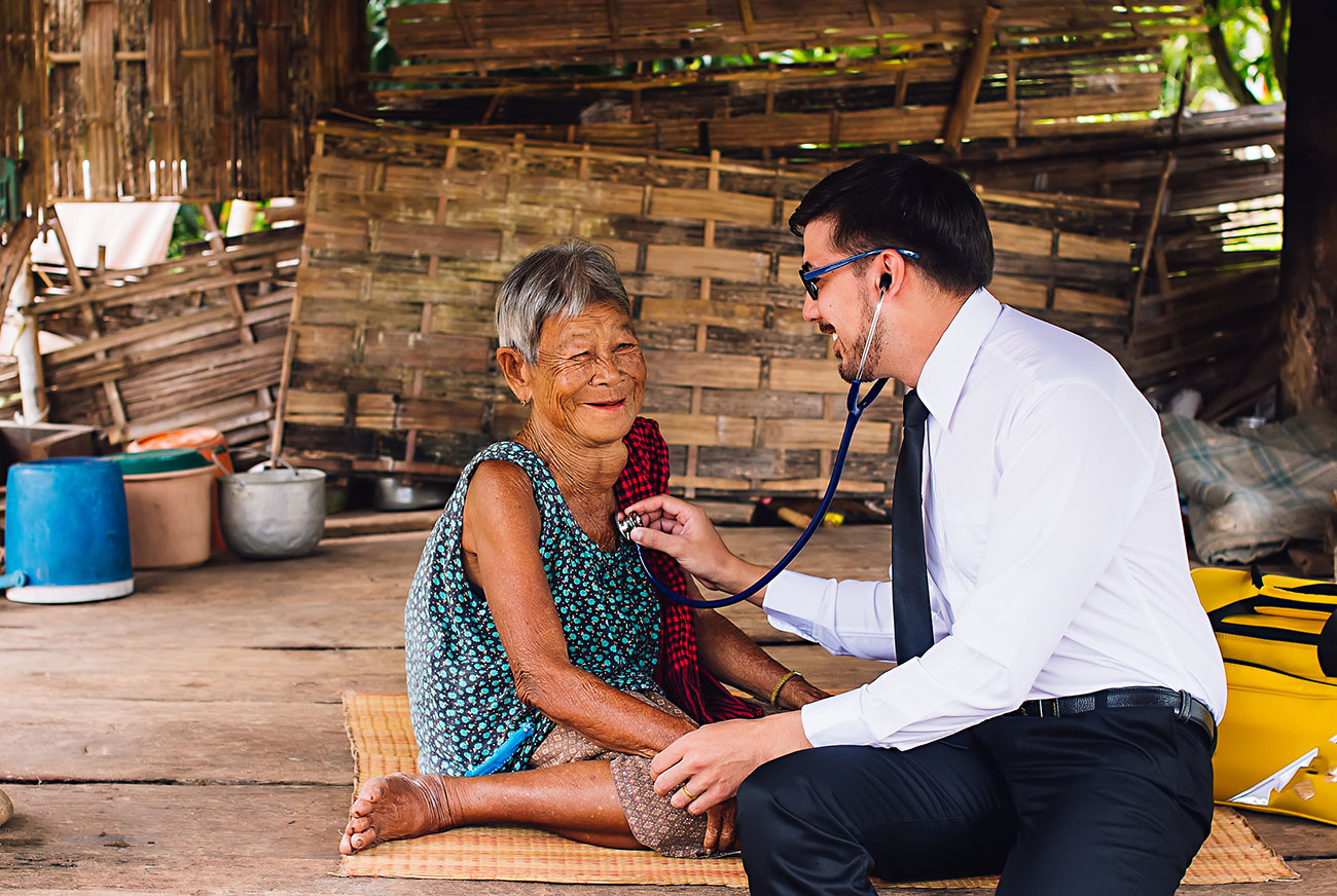 male doctor listening to heart beat and breathing of elderly woman