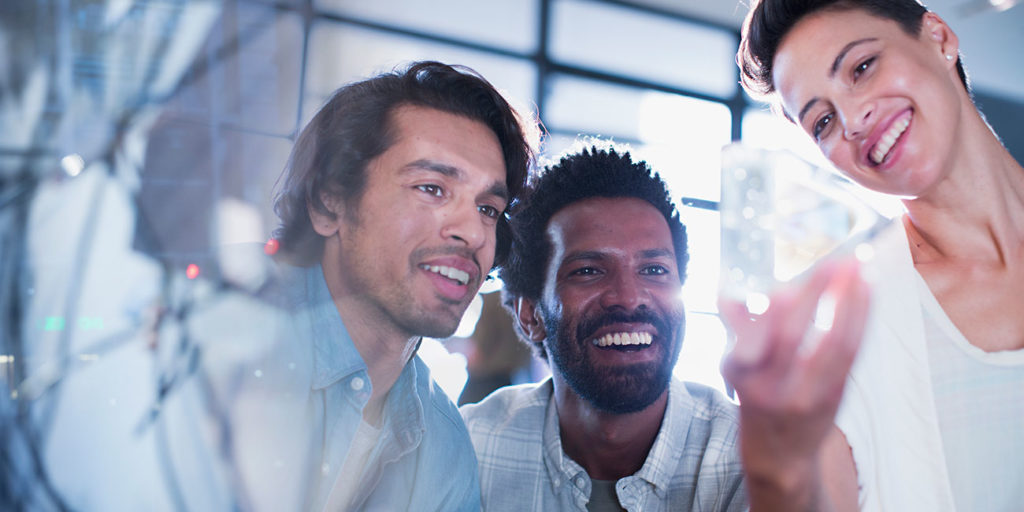 Smiling, curious, innovative entrepreneurs examining glass triangle prototype