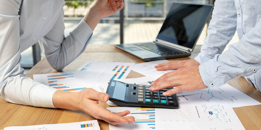 Cropped profile side view of two co-workers calculating corporate taxable income 