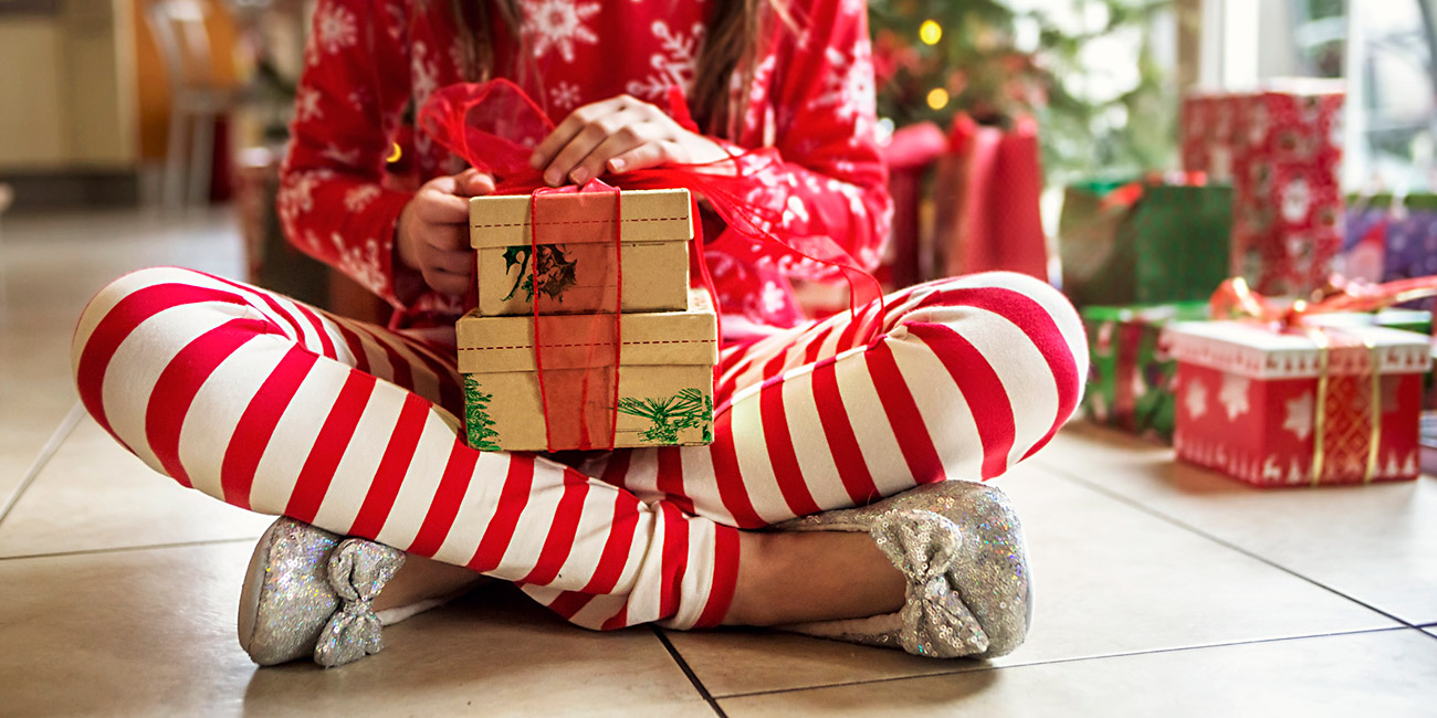 A young girl sitting opening her colorful, pretty gift boxes on Christmas morning