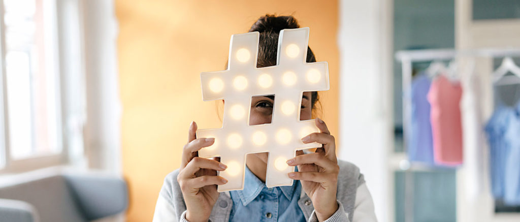 social media marketing young woman hiding behind hashtag in studio