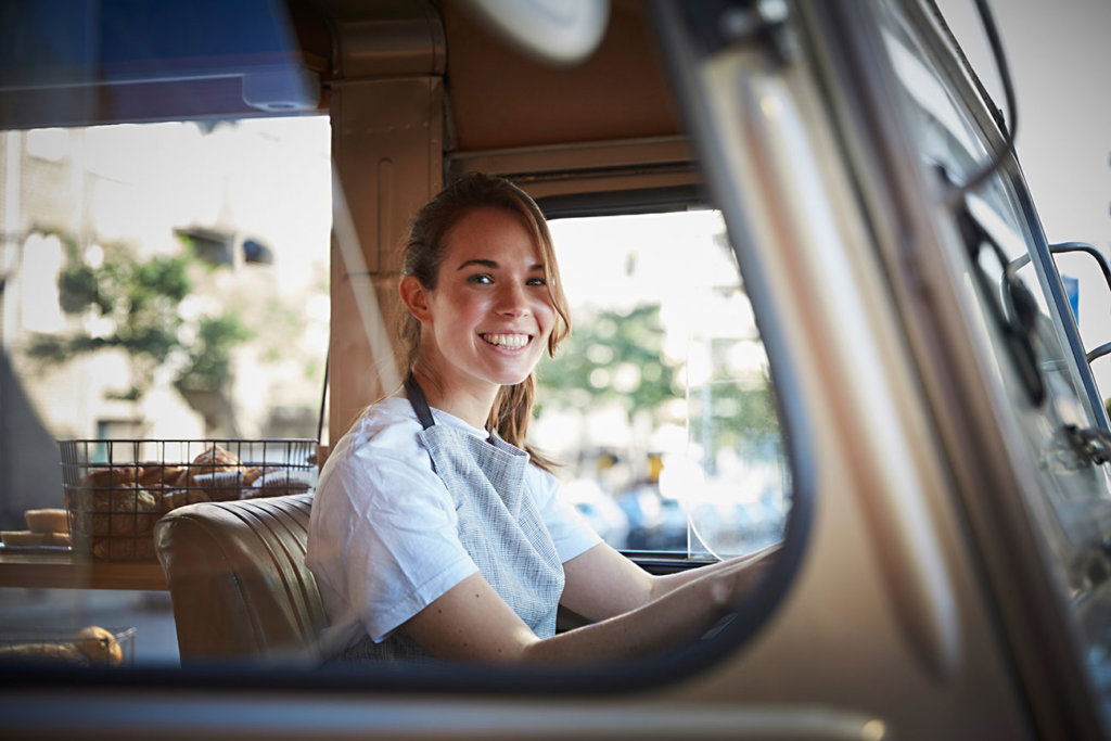 smiling young woman entrepreneur at the wheel of a food truck