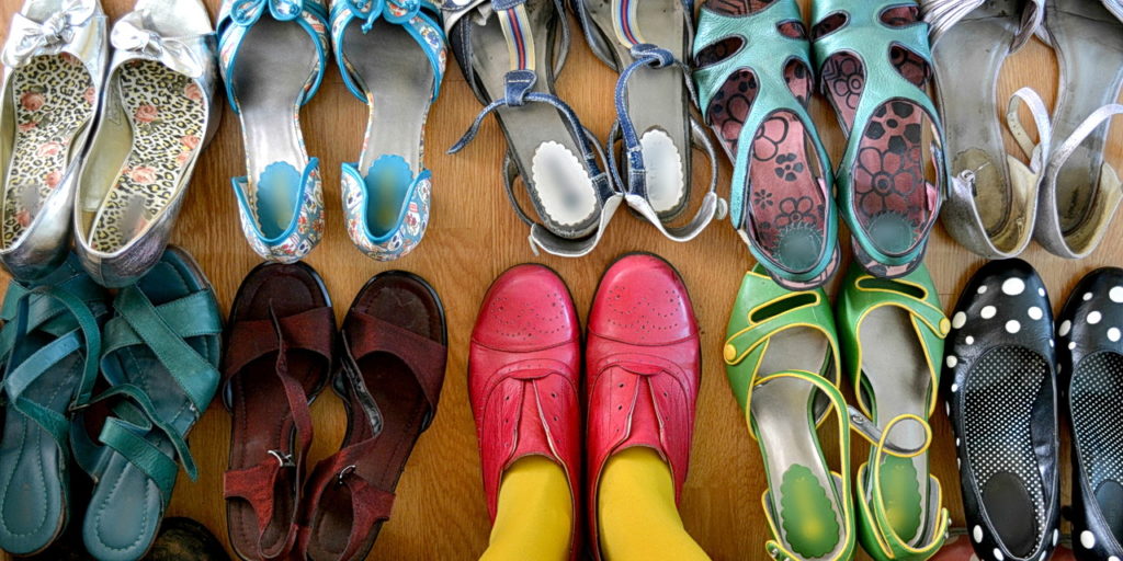 Legs in yellow stocking, pink shoes, surrounded by shoes.