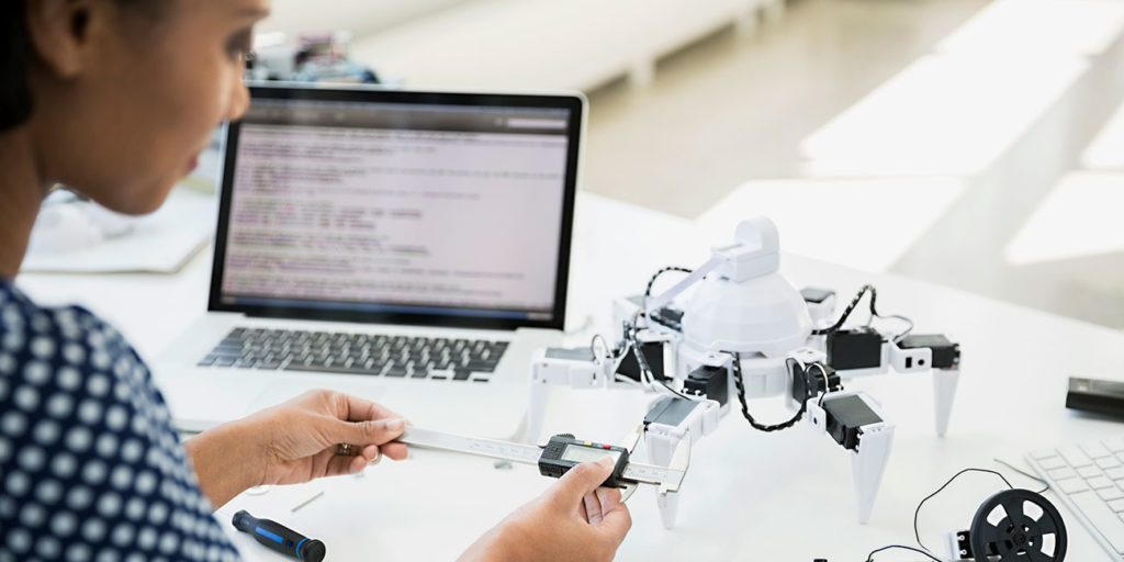 african-american Engineer measuring robot with calipers