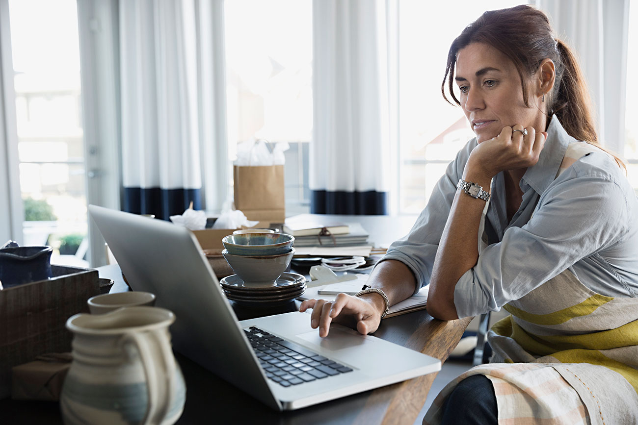 Woman calculating profit on laptop computer