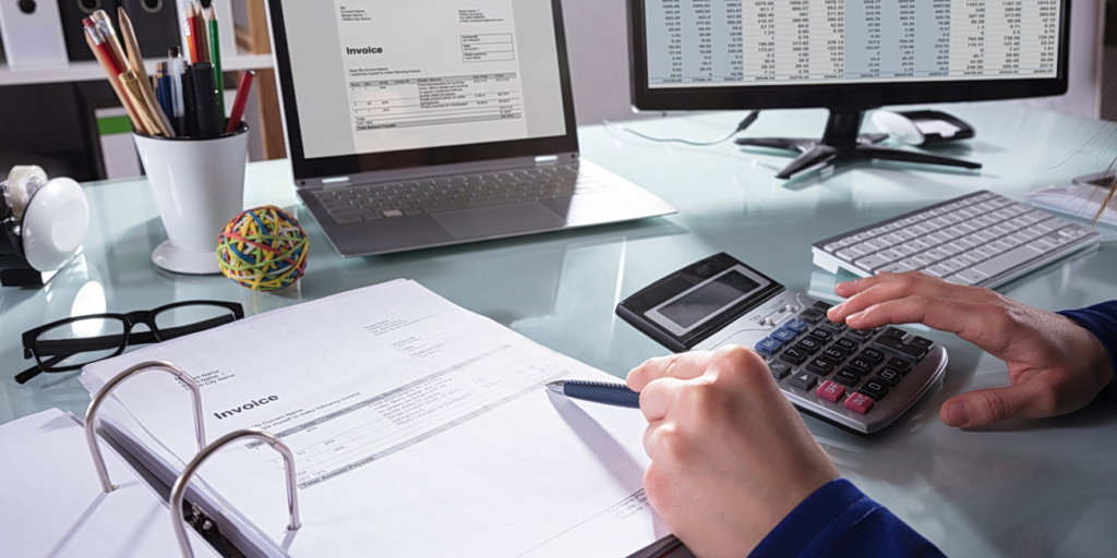Close-up Of A Businessperson's Hand Calculating Invoice At Workplace