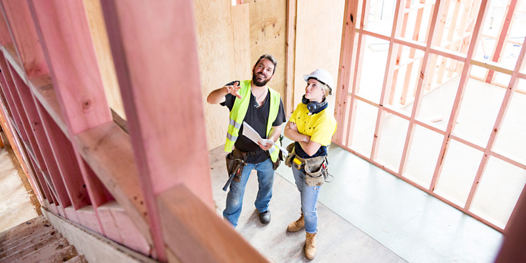 male and female construction workers discuss the building plans inside the building site