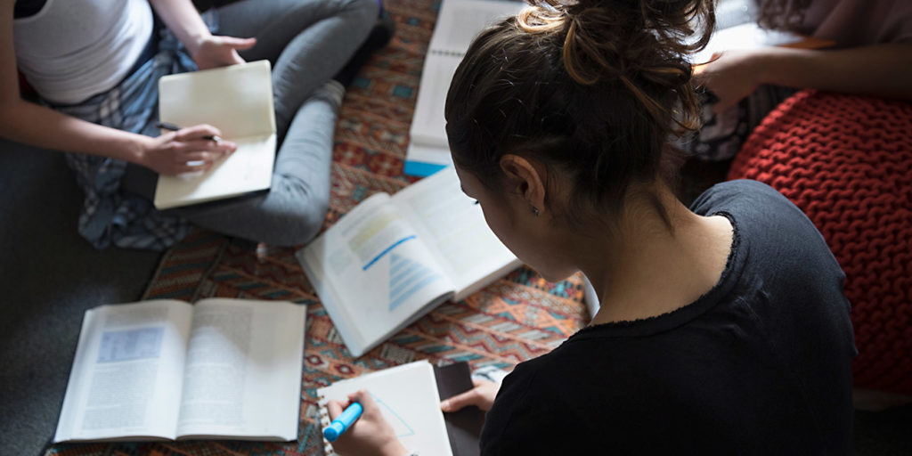 Female college students studying on floor in dorm room