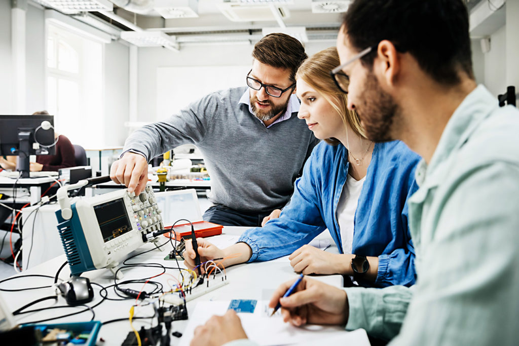 An engineering tutor showing his students how to use some electronic equipment